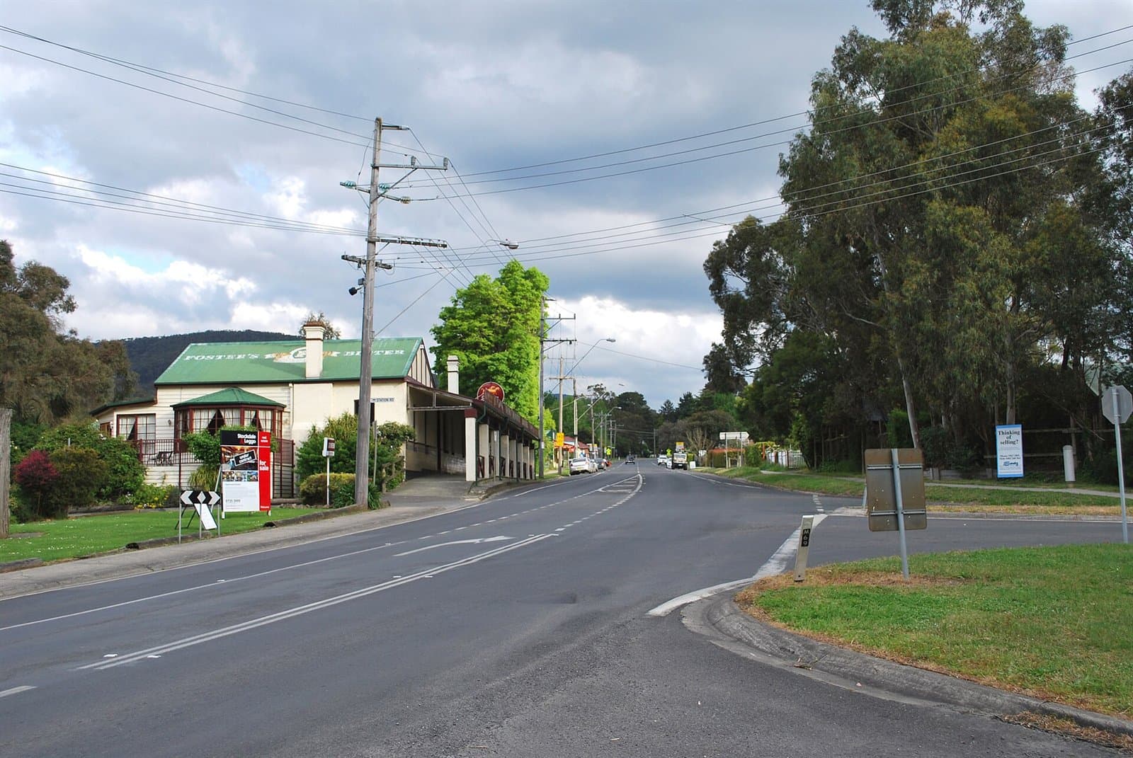 The Warburton Highway bending through Wesburn, with a building and trees beside it